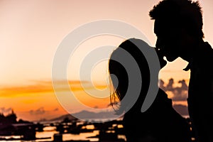 Silhouette of couple kiss on the beach at the sunrise and sunset